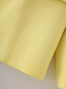 Macro shot of light yellow satin fabric showing fine twill texture and smooth finish