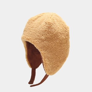 Detail of warm winter trapper hat with beige faux fur lining and brown corduroy exterior