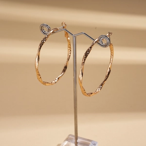 Detailed view of large gold twisted hoop earrings with a hammered metallic texture