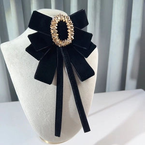 Elegant black velvet bow brooch with gold crystal center displayed on a mannequin