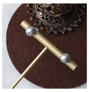 Macro shot of silver grey freshwater pearl earrings on a premium metal display stand