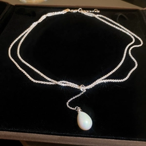 Macro detail of elegant silver layered heart necklace with pearls in a black velvet box