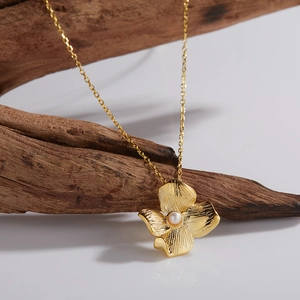 Macro detail of a golden flower pendant with a central pearl on a rustic wood branch