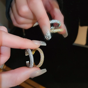Close-up of gold and silver C-shaped twisted rings with shimmering micro-pave zircons