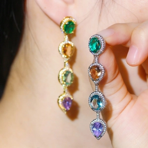 Detailed macro of crystal drop earrings with green, amber, blue, and purple stones