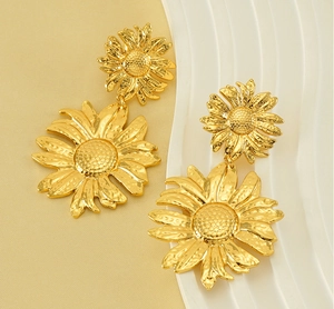 Macro detail of gold sunflower earrings featuring hammered textures and dual-layer petals