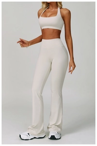Detail of high-waisted yoga pants with flare leg and halter sports bra in cream white