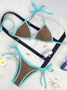 Detailed flat lay of brown and blue color-block bikini set with beach vacation accessories