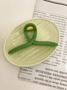 Detail of a grass green 13cm shark hair claw clip on a ceramic tray with a modern style