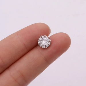 Macro shot of silver flower stud earring with micro-inset zircons held by fingers