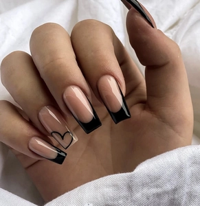 Close-up of long square press-on nails with black French tips and minimalist heart detail