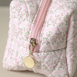 Macro shot of floral quilted cotton makeup bag featuring a pink zipper and gold round puller