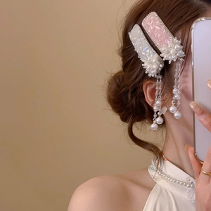 Detail of floral hair clip with crystal accents and hanging pearl tassels on model