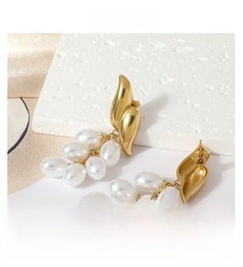 Detailed macro view of gold wing-shaped earrings with clustered white pearl droplets