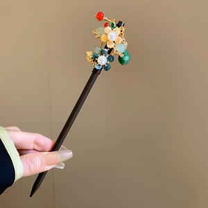 Detail of a floral hair stick with blue flowers and tassels held in hand