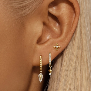 Gros plan de trois boucles d'oreilles en argent S925 doré avec zircons sur l'oreille