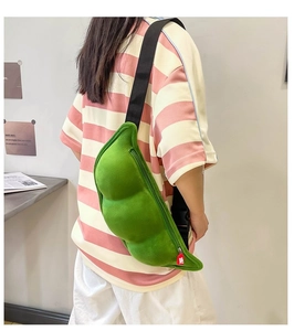 Rear view of a model wearing a green plush pea-shaped crossbody bag with black strap
