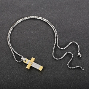 Détail d'un pendentif croix bicolore or et argent avec diamant sur chaîne maille
