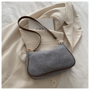 Detail of grey herringbone fabric underarm bag with brown leather trim and gold hardware