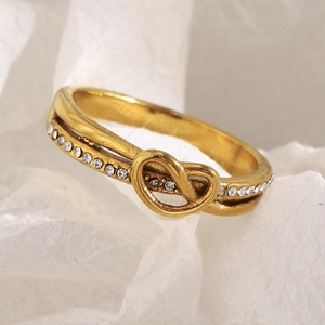 Macro detail of gold-plated knot ring with sparkling white zircon stones and metal texture
