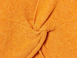 Macro detail of bright orange knit fabric with twist knot design and soft texture