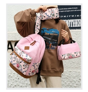 Detailed set of pink floral canvas backpack, lunch bag, and pencil case worn by a model