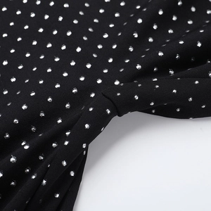 Detail view of black strapless jumpsuit fabric with sparkling silver polka dot patterns
