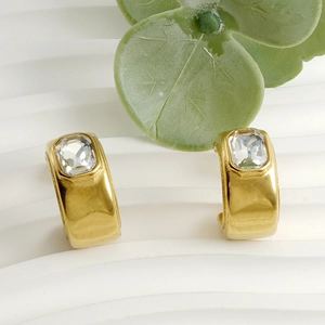 Boucles d'oreilles créoles dorées 18K en forme de C avec cristal sur support blanc