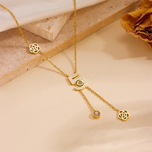 Detail of gold number 5 pendant with white inlay and crystal on floral chain