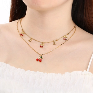 Double-layer gold chain necklace featuring red enamel cherry pendants on a model's neck