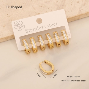 Close-up of three pairs of gold stainless steel U-shaped earrings with white rhinestones