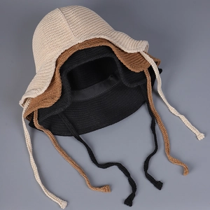 Flat lay detail showing beige, brown, and black breathable knit sun hats with tie straps