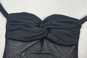 Macro detail of black sheer mesh dress featuring knot twist design and textured fabric