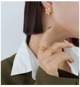 Detail of matte gold petal earrings and minimalist geometric rings on model