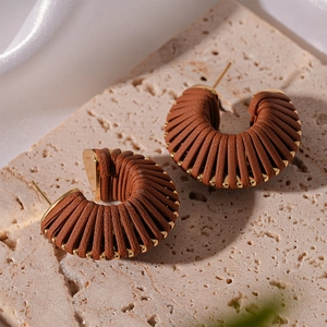 Detailed view of brown faux leather woven C-shaped earrings with gold metal accents