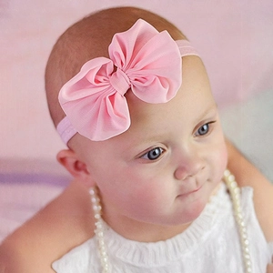 Detailed view of baby wearing a pink chiffon bow headband with a wide elastic band