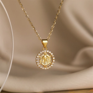 Makroaufnahme einer goldenen Halskette mit Marienanhänger und weißen Zirkonia-Steinen