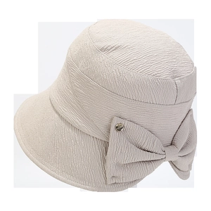 Close-up of beige sun hat featuring textured fabric and a decorative side bow with metal buckle