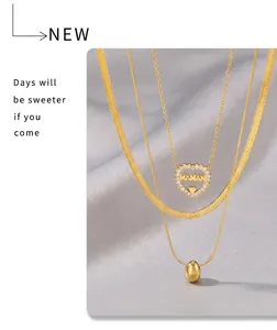 Detailed view of triple-layered gold necklaces with heart pendant and snake chain