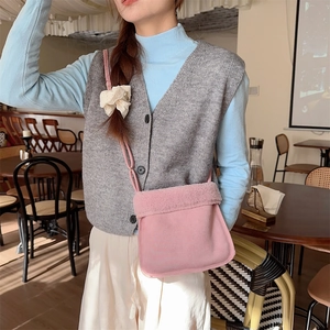 Détail du sac bandoulière rose en suédine avec bordure en peluche douce sur modèle