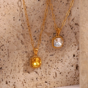 Detail of gold paperclip chain necklace with faceted square yellow gemstone pendant