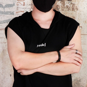 Detail of a black punk style woven bracelet and silver ring on a male model's wrist