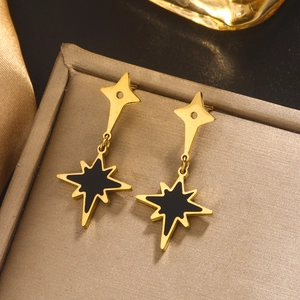 Macro shot of 18K gold plated star earrings with black shell inlay on a gold metal tray