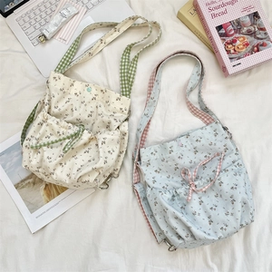 Detail of floral canvas crossbody bags with checkered straps and drawstring pockets