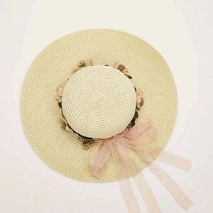 Top view of a wide brim straw sun hat with floral wreath and pink organza ribbon details