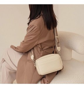 Chic beige lychee grain PU crossbody bag with designer wide woven strap on a model