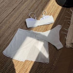 Flat lay of white three-piece bikini set with waffle texture and mesh beach skirt