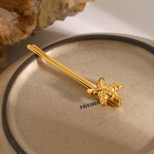 Makroaufnahme der goldenen Seestern-Haarklammer mit Metalldetails auf Keramiktablett