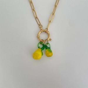 Detailed view of a gold chain necklace with bright yellow lemon and green leaf pendants
