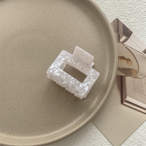 Dettaglio della pinza per capelli quadrata effetto marmo su un vassoio di ceramica